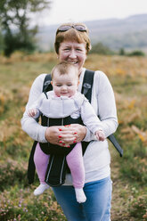 Eine Frau mit einem Baby in einer Babytrage bei einem Herbstspaziergang. - MINF04808