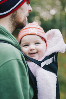 Ein Baby in einem Tragetuch, das von seinem Vater getragen wird, im Winter im Freien. - MINF04827