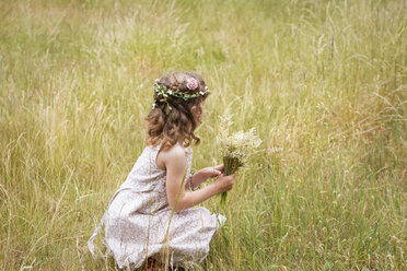 Junges Mädchen mit Blumen im Haar pflückt Wildblumen auf einer Wiese. - MINF04882