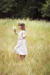 Young girl with flowers in her hair picking wild flowers in a meadow. - MINF04884