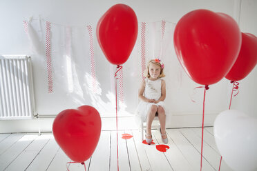 Junges Mädchen posiert für ein Foto in einem Fotostudio, umgeben von roten Luftballons. - MINF04886