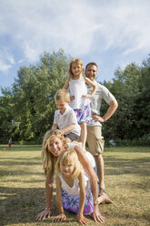 Familie mit drei Kindern beim Spielen in einem Park. - MINF04900