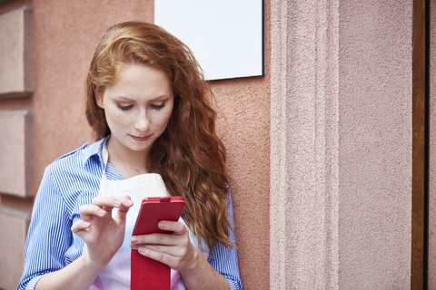 Junge Frau benutzt ein Mobiltelefon während einer Arbeitspause, lizenzfreies Stockfoto