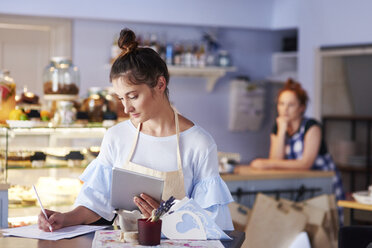 Frau arbeitet in einem Café und macht sich Notizen - ABIF00827