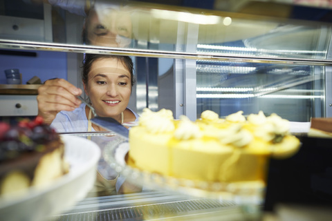 Frau arbeitet in einem Café und serviert ein Stück Kuchen, lizenzfreies Stockfoto