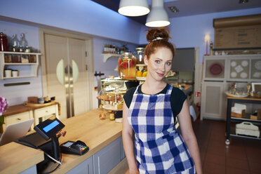 Portrait of smiling young woman at the counter in a cafe - ABIF00843