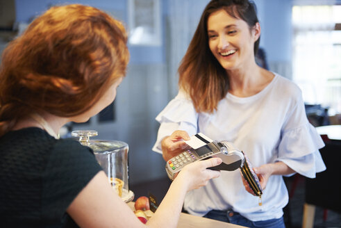 Glücklicher Kunde, der in einem Café mit Kreditkarte bezahlt - ABIF00858