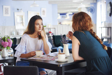 Zwei Frauen unterhalten sich und trinken Kaffee in einem Cafe, lizenzfreies Stockfoto