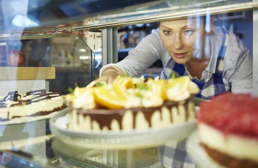 Frau arbeitet in einem Café und serviert ein Stück Kuchen - ABIF00866