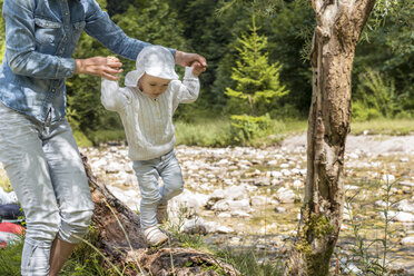 Mutter hält die Hände ihrer Tochter und balanciert auf einem Baumstamm - DIGF04733