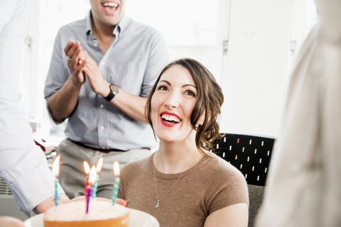 Weibliche Büroangestellte erhält Geburtstagskuchen, lizenzfreies Stockfoto