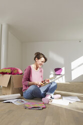 Woman sitting on wooden floor with box - CUF43784