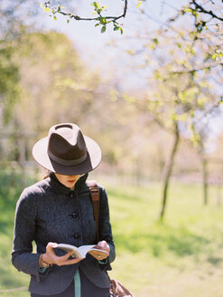 Eine Frau mit einem Hut, die ein Buch liest. - MINF04903
