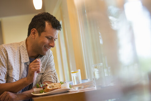 A man eating a snack in a cafe. - MINF04905