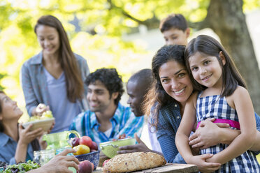 Ein Sommerfest im Freien: Erwachsene und Kinder lächeln und schauen in die Kamera. - MINF04915