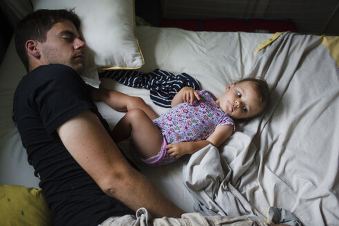 Ein Vater liegt schlafend in einem Bett neben seiner kleinen Tochter, Blick von oben. - MINF04991