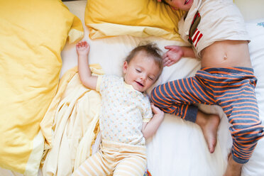 Ein Bruder, der neben seiner Schwester schläft, ein Kleinkind und ein kleiner Junge, die Seite an Seite in einem Bett liegen. - MINF04998