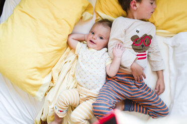 Ein Bruder, der neben seiner Schwester schläft, ein Kleinkind und ein kleiner Junge, die Seite an Seite in einem Bett liegen. - MINF04999