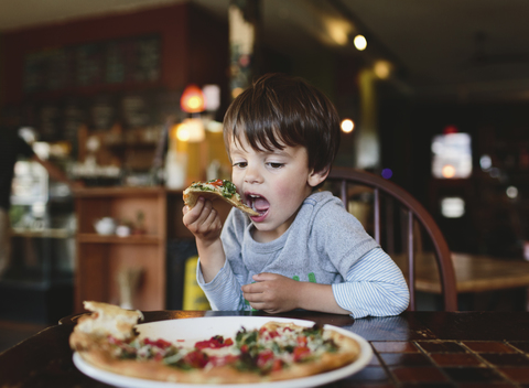 Ein Junge, ein Kind isst Pizza in einem Restaurant., lizenzfreies Stockfoto