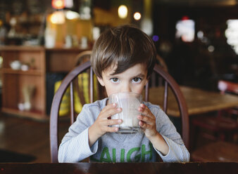 Ein Junge, ein Kind, das in einem Restaurant ein Glas Milch trinkt. - MINF05034