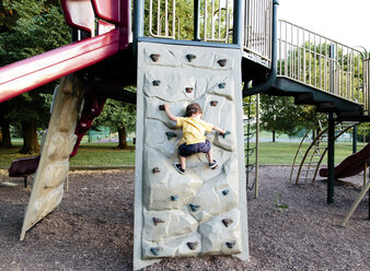 Ein Kind, ein Junge klettert auf einem Spielplatz an einer Kletterwand. - MINF05043