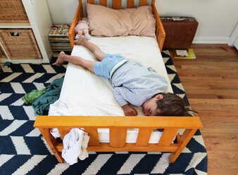 Ein Junge, ein Kind liegt schlafend auf einem Bett. - MINF05045