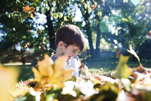 Ein Kind, ein Junge, der mit gefallenen Herbstblättern spielt. - MINF05060