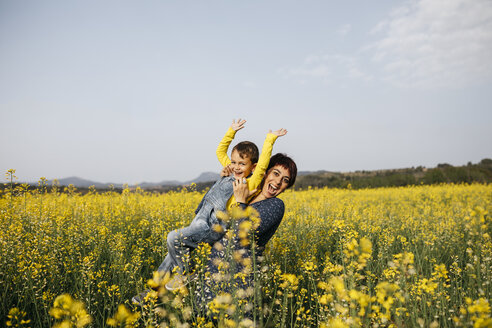 Spain, portrait of happy mother and her little son up standing in rape field - JRFF01775