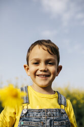 Portrait of happy little boy with picked yellow flower in nature - JRFF01781