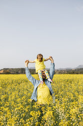 Spain, father and baby girl having fun together in a rape field - JRFF01783