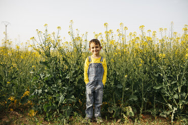 Portrait of smiling little boy standing in front of blooming rape field - JRFF01790