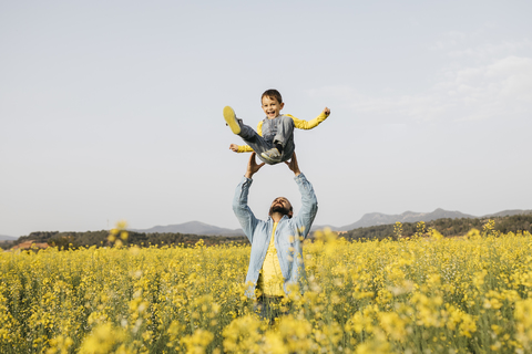 Spanien, Vater und kleiner Sohn haben Spaß zusammen in einem Rapsfeld, lizenzfreies Stockfoto