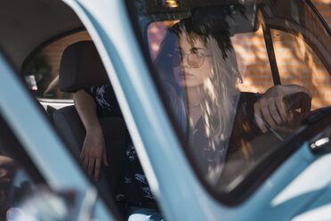 Young woman wearing sunglasses sitting in a car - KKAF01348