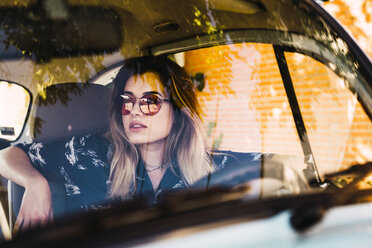 Junge Frau mit Sonnenbrille, die in einem Auto sitzt - KKAF01353