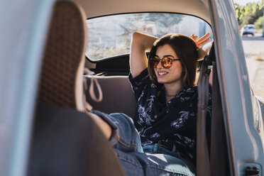 Smiling young woman wearing sunglasses sitting in a car - KKAF01358