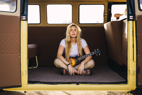 Junge Frau in einem Lieferwagen mit einer Gitarre, lizenzfreies Stockfoto