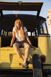 Junge Frau mit Skateboard in einem alten Lieferwagen sitzend - KKAF01381