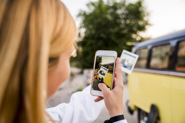 Junge Frau, die mit ihrem Handy ein Sofortfoto an einem Lieferwagen aufnimmt - KKAF01397