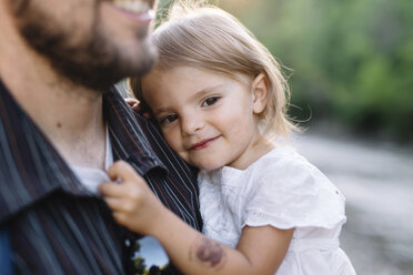 Bearded man standing outdoors, holding smiling young girl. - MINF05077