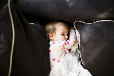 A toddler girl asleep on the cushions of a sofa. - MINF05090