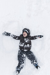 Boy, child lying and playing in snow. - MINF05128