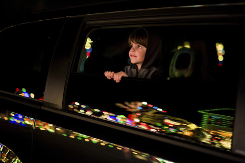 Junge, Kind lehnt sich aus einem Autofenster und betrachtet die Weihnachtsbeleuchtung. - MINF05140