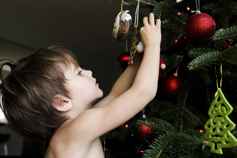 Boy, child decorating a Christmas tree with ornaments. stock photo