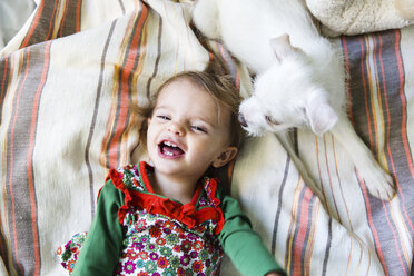 A puppy and a baby girl lying on a bed. - MINF05166