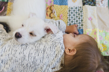 Ein Welpe und ein Baby schlafen auf einer Patchwork-Decke. - MINF05172