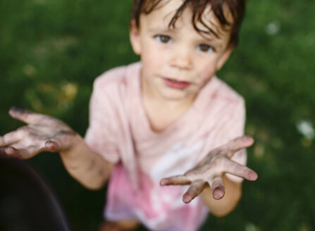 Junge mit schmutzigem Gesicht und schmutzigen Händen steht im Freien und schaut in die Kamera. - MINF05178