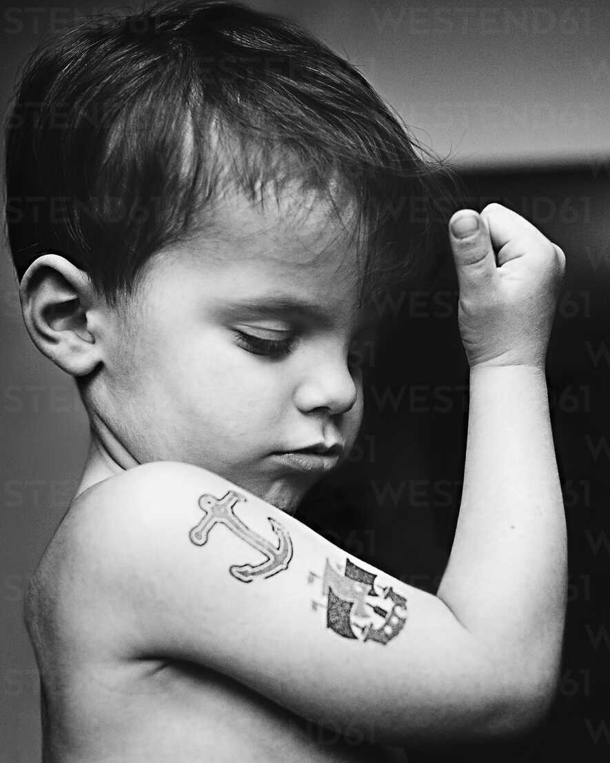 close up of young boy with fake anchor and ship tattoos on his biceps MINF05180