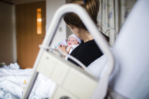 Nahaufnahme einer Frau im Krankenhausbett, die ihr neugeborenes Baby hält. - MINF05187