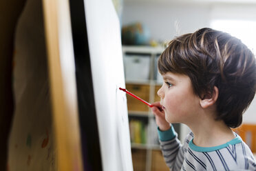 Nahaufnahme eines Jungen mit braunem Haar, der an einer Staffelei steht und zeichnet. - MINF05199