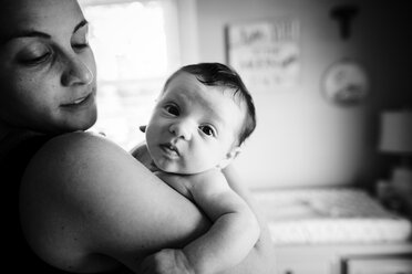 Nahaufnahme einer Frau, die ein kleines Baby im Arm hält und in die Kamera schaut. - MINF05221